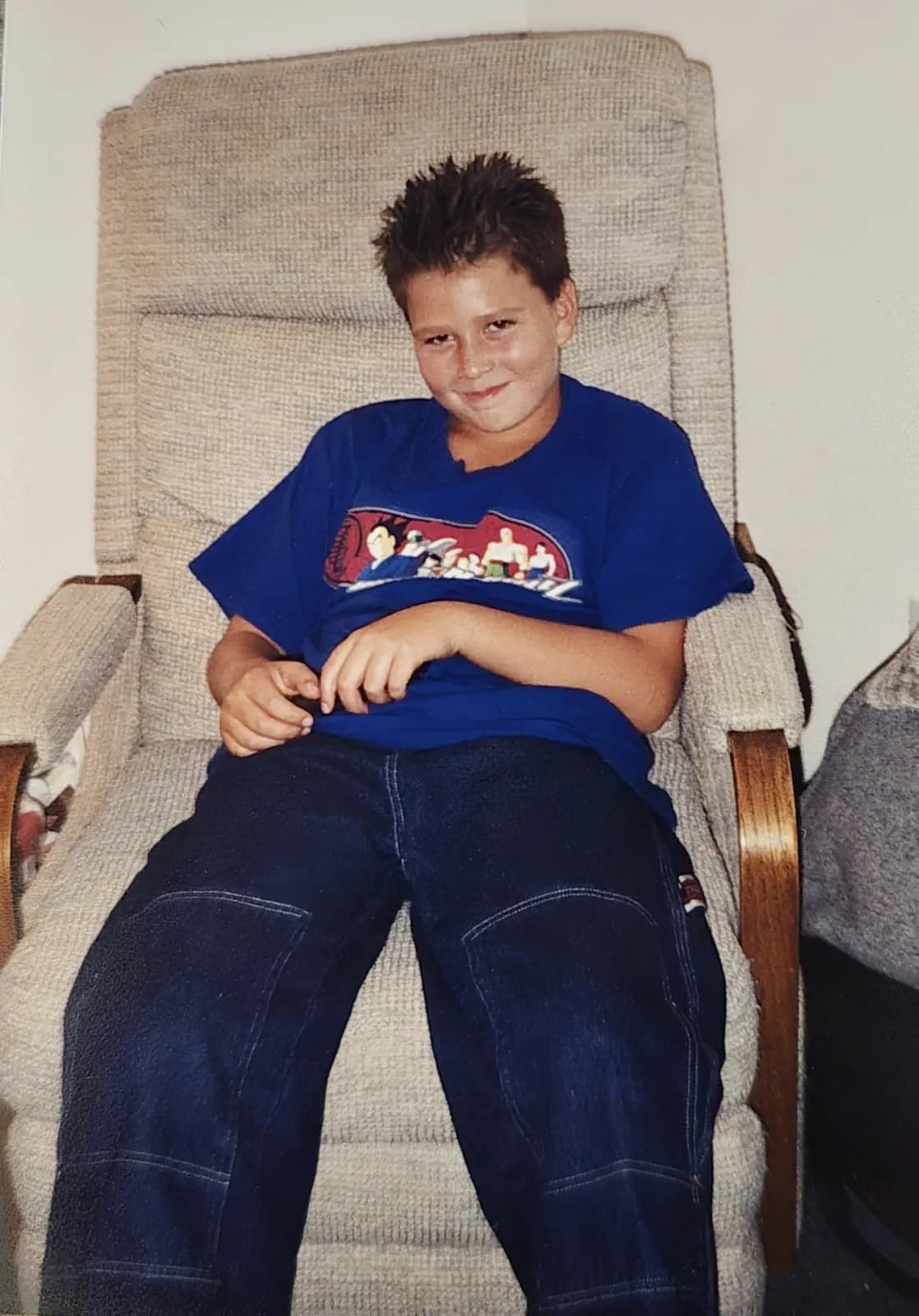 Ken around age 12, grinning in an armchair with spiked hair.